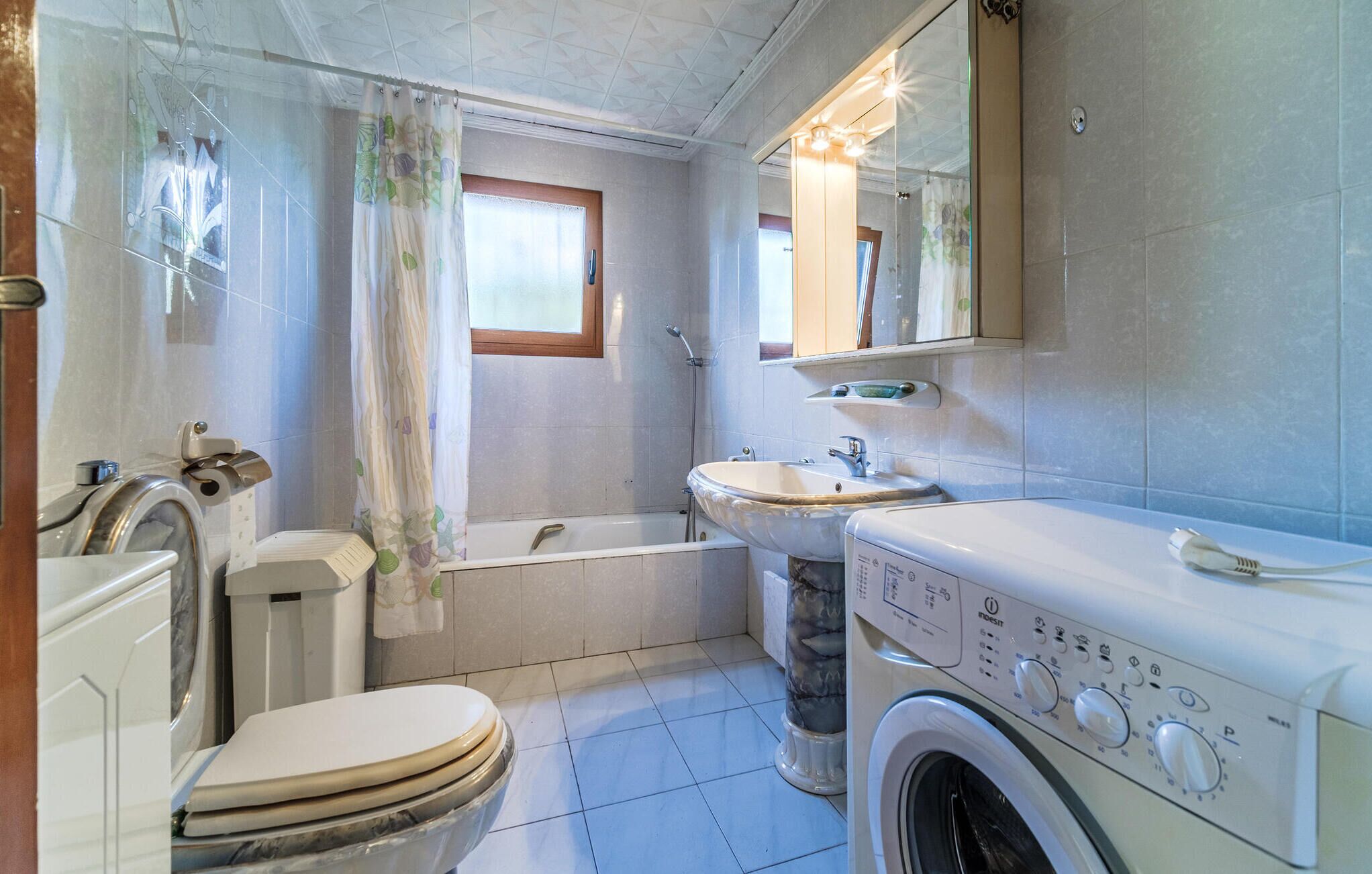 A compact bathroom with a toilet, washing machine, sink, and bathtub.