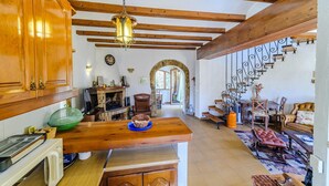 A spacious kitchen with wooden beams, a stone archway, and a dining area with leather furniture. - Pet friendly home in Els Poblets (Els Poblets)