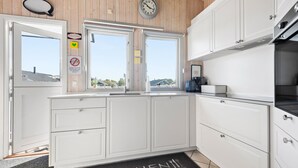 Cocina moderna con armarios blancos, un reloj, un cartel de bienvenida y un letrero de no fumar.