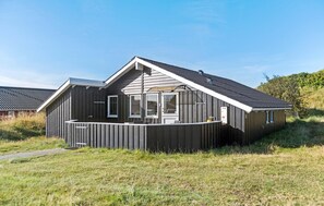 Ein modernes, eingeschossiges Gebäude mit Satteldach und überdachter Veranda.