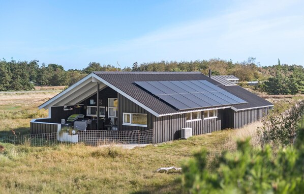 Ein modernes Haus mit geneigtem Dach und Solaranlagen.