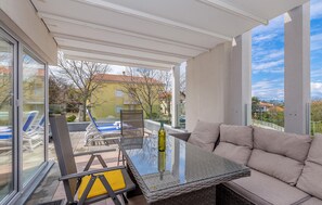 Un balcon avec une table en verre, un canapé confortable et un fauteuil.