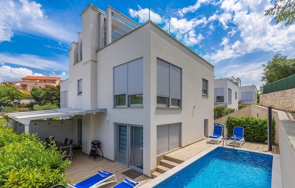 Une maison moderne à deux étages, dotée d’une piscine, d’un patio couvert et offrant une vue sur le quartier environnant.