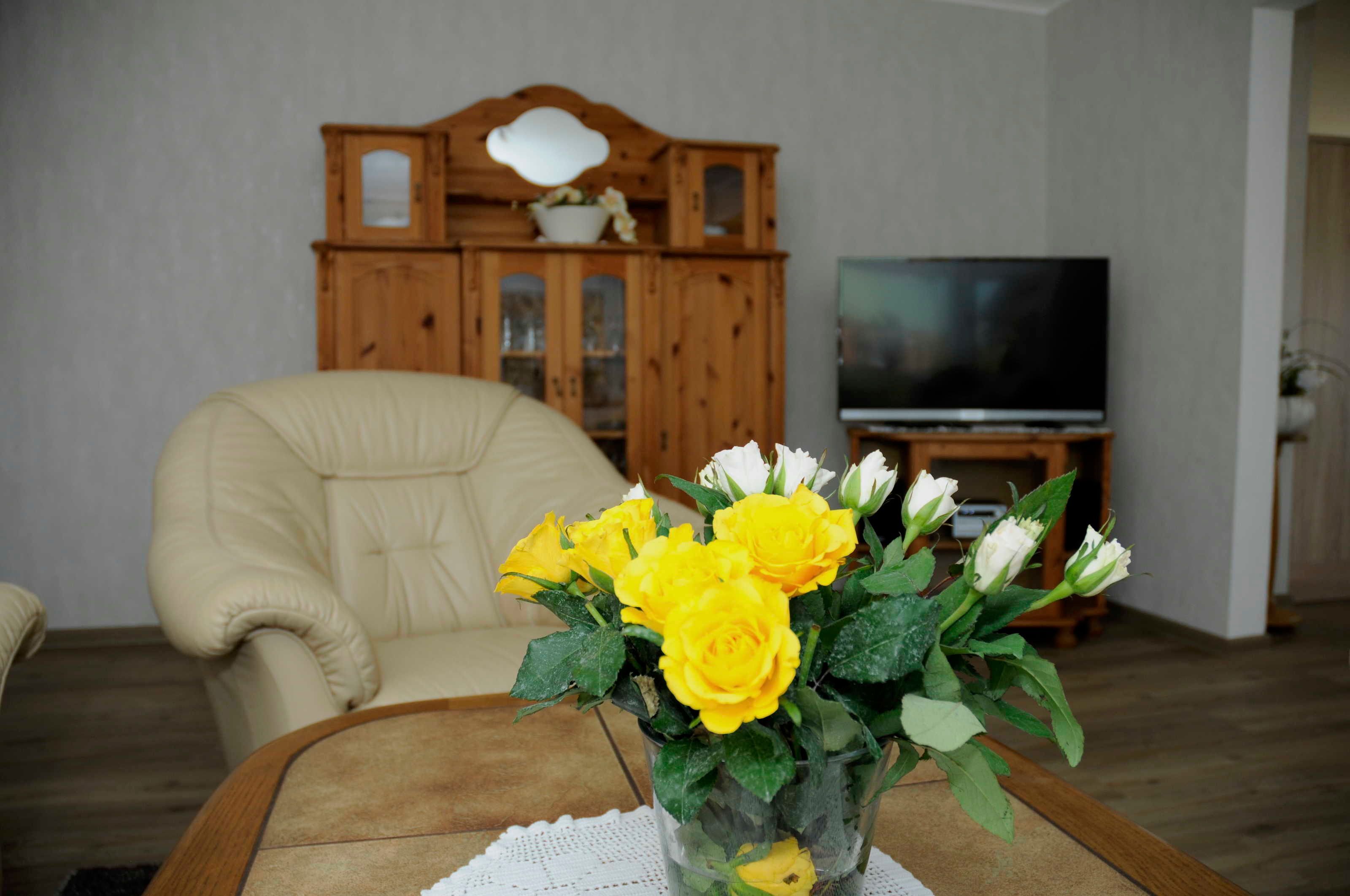 Een woonkamer met een beige fauteuil, een houten kast en een televisie.