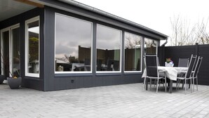 A modern house with large windows, a patio with a table and chairs, and a flower planter. - Vacation apartment Meer, Germany (Hasselberg)