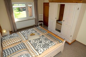A bedroom with a large bed, a wardrobe, a window, and a chair.