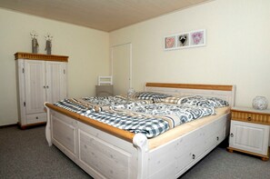 A bedroom with a double bed, a wardrobe, a bedside table, and a wall with framed pictures. - Vacation apartment Meer, Germany (Hasselberg)