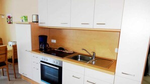A compact kitchen with white cabinets, a stove, oven, and a coffee maker.