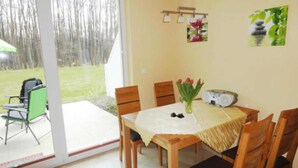 A dining area with a table set for four, chairs, a vase with flowers, and a radio on the table.