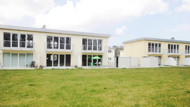 A modern building with a flat roof, large windows, and a grassy courtyard.
