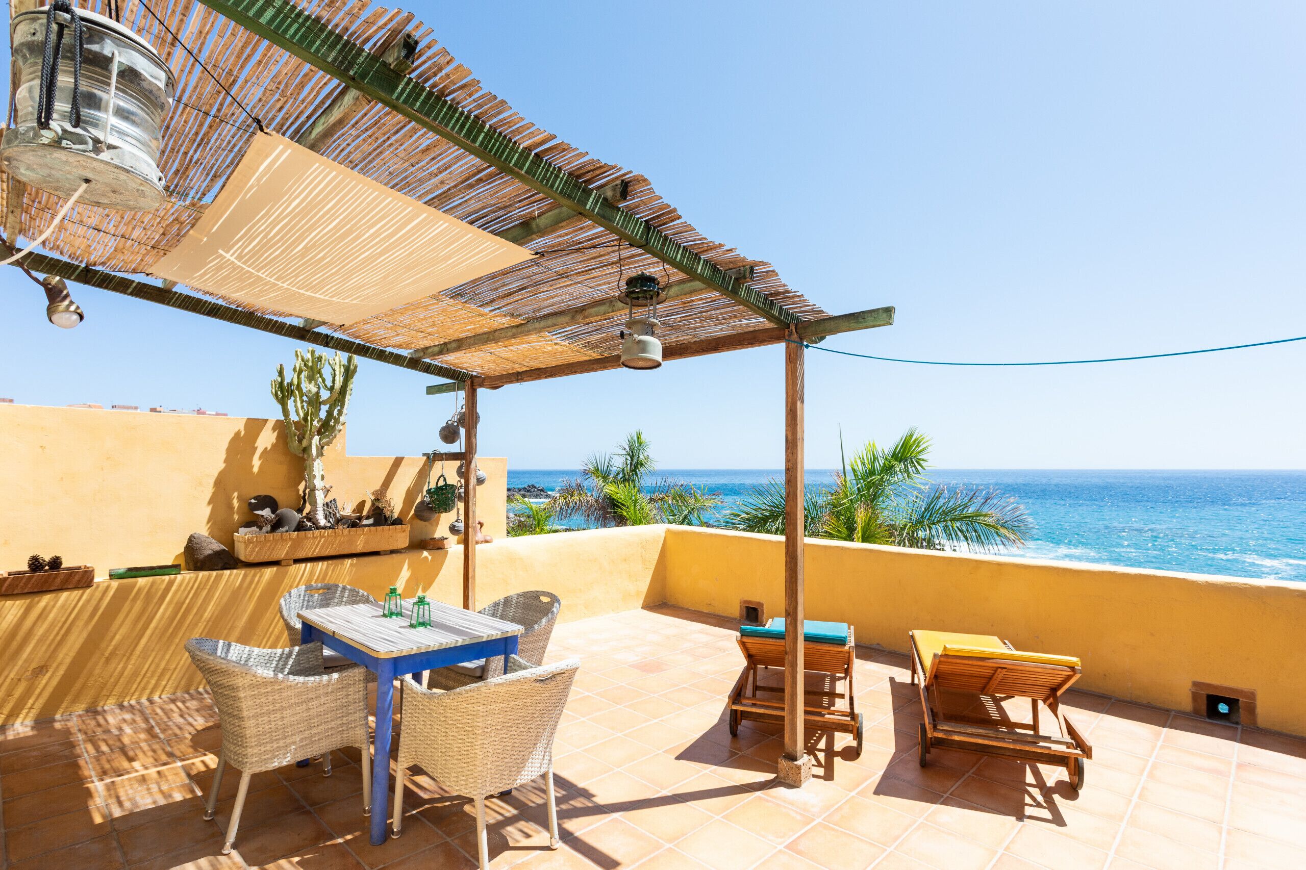 Une terrasse meublée de mobilier en osier, avec une table et une chaise, donnant sur l’océan.