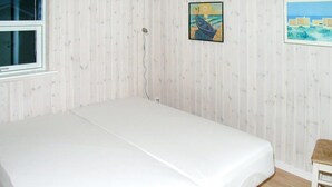 Ein Zimmer mit einem Einzelbett, einem Fenster und zwei Bildern an der Wand.