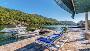 Un port de plaisance avec des bateaux amarrés, des chaises longues et une vue sur un lac entouré de collines.