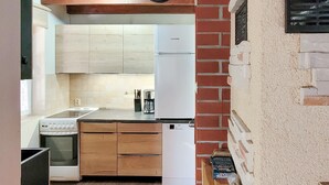 Una cocina compacta con armarios de madera, un refrigerador blanco, una cafetera y un microondas.