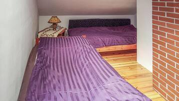 Una habitación pequeña con dos camas, una mesita de noche y una lámpara.