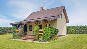 Una casa de un piso con techo inclinado, un porche con escalones de madera y una chimenea.
