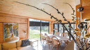 A modern dining area with a wooden ceiling, large windows, and a central table surrounded by wicker chairs. - Amazing home in Ebeltoft with sauna (Ebeltoft)