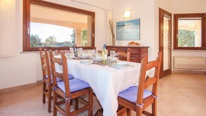 A dining area with a table set for four, wooden chairs, and a view through the window.