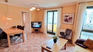 A living room with a TV, a sofa, a table, and a chair. - (213) 2-room apartment - apartment house Villa Laura (Kühlungsborn)