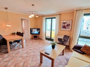 A living room with a TV, a sofa, a table, and a chair. - (213) 2-room apartment - apartment house Villa Laura (Kühlungsborn)