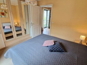 A bedroom with a large bed, a wardrobe, and a door leading to a balcony. - (213) 2-room apartment - apartment house Villa Laura (Kühlungsborn)