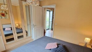 A bedroom with a large bed, a wardrobe, and a door leading to a balcony. - (213) 2-room apartment - apartment house Villa Laura (Kühlungsborn)