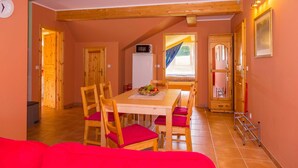 A dining area with a wooden table and chairs, a clock on the wall, and a view of the outside. - Apartment 5 - Usedom Landhaus Morgenitz (Mellenthin OT Morgenitz)