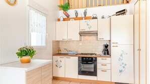 Een keuken met witte kastjes, een fornuis, oven en een koffiezetapparaat.