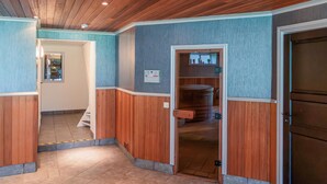 Ein Korridor mit Holzwandverkleidung, einer Tür zu einem Badezimmer und einem sichtbaren Warmwasserbereiter.