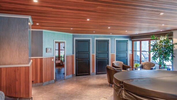 Ein modernes Interieur mit Holzwandverkleidung, Steinfliesenboden und einer großzügigen Sitzecke mit Tisch.