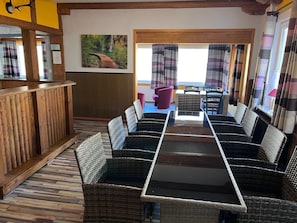 Ein Restaurant mit Korbmöbeln, einer Holztheke und einem Landschaftsbild.