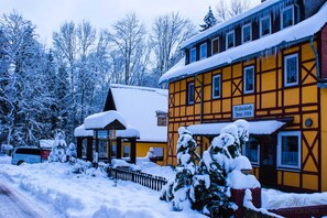 A traditional half-timbered building with a snow-covered roof and a sign indicating it is a hotel.