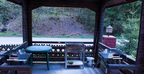 An outdoor patio with a table and chairs, a metal grill, and a lantern.