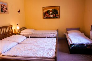 A room with two beds, a nightstand with a lamp, and a painting on the wall.