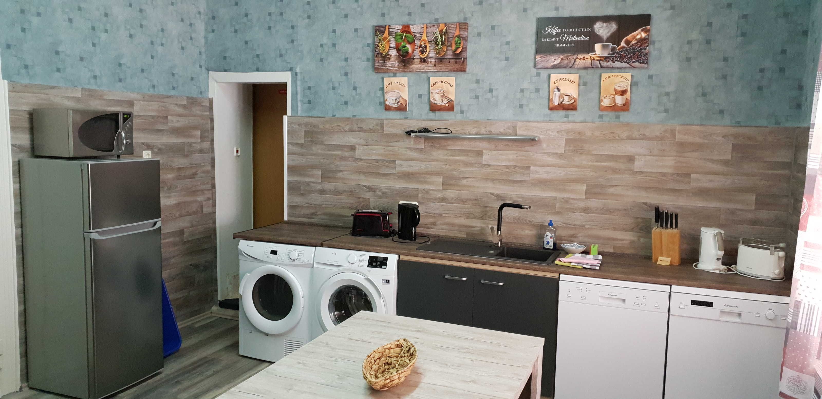 Une cuisine compacte équipée d’un four à micro-ondes, d’un grille-pain, d’un évier et d’un lave-linge.