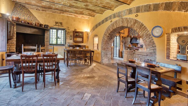 Un intérieur rustique avec des arches en briques, un sol en pierre, des meubles en bois et un four en briques.