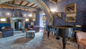 Une vaste pièce agrémentée d’un magnifique piano à queue, de fauteuils confortables et d’une arche en pierre.