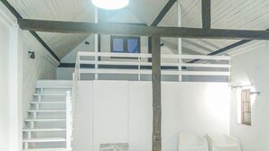 Ein Zimmer mit einem Etagenbett, einer Treppe, einem kleinen Fenster und einem Stuhl.