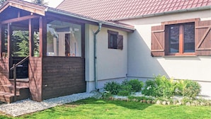 Ein Haus mit überdachter Veranda, einem kleinen Garten und einem Kiesweg.