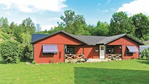 Punainen puinen rakennus, jossa on kuisti, ovi ja kaksi ikkunaa, joiden yläpuolella on markiisi.