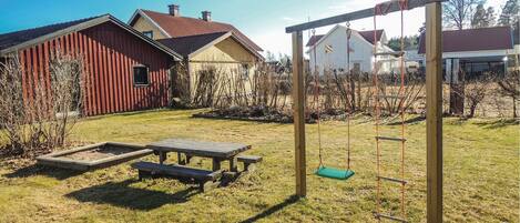 A backyard with a swing set, picnic table, and a red barn.