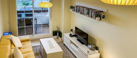 Ein Wohnzimmer mit einer Couch, Fernseher, Bücherregal und einem Tisch mit einem Fußball.