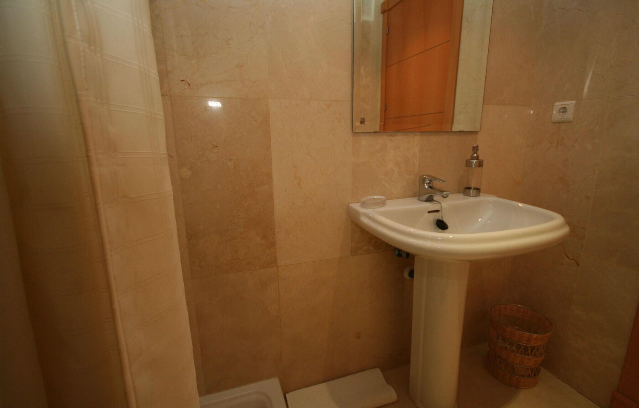 A bathroom with a white sink, a mirror, and a wooden cabinet.