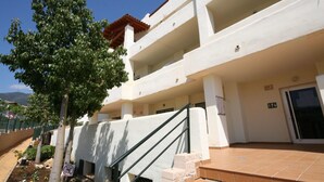 Un immeuble à plusieurs étages, à la façade blanche, doté d’un toit recouvert de tuiles rouges et d’un escalier menant à l’entrée.