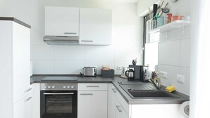 Una cocina moderna con armarios blancos, horno empotrado, tostadora y pileta.