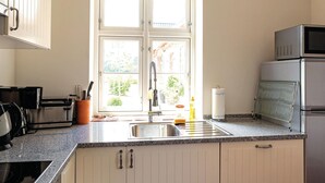 Een keuken met een raam, roestvrijstalen apparatuur en een spoelbak.