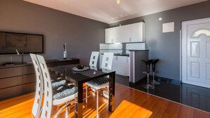 Un espacio habitable moderno con comedor, cocina y un televisor de pantalla plana grande montado en la pared.