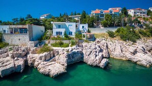 Un pueblo costero con edificios de piedra, agua turquesa cristalina y un litoral rocoso.
