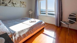 Un dormitorio con cama, una silla, un ventanal con vistas y decoración en las paredes.