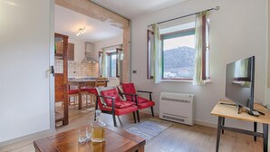 Un espacio habitable compacto con comedor, televisión y vistas a un paisaje montañoso.
